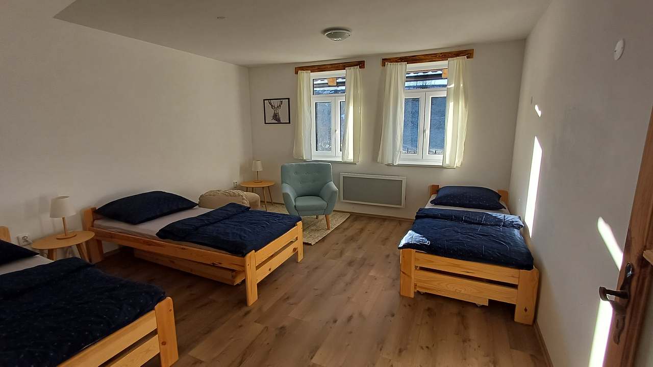 Ložnice se třemi borovicovými jednolůžky a tmavě modrým povlečením